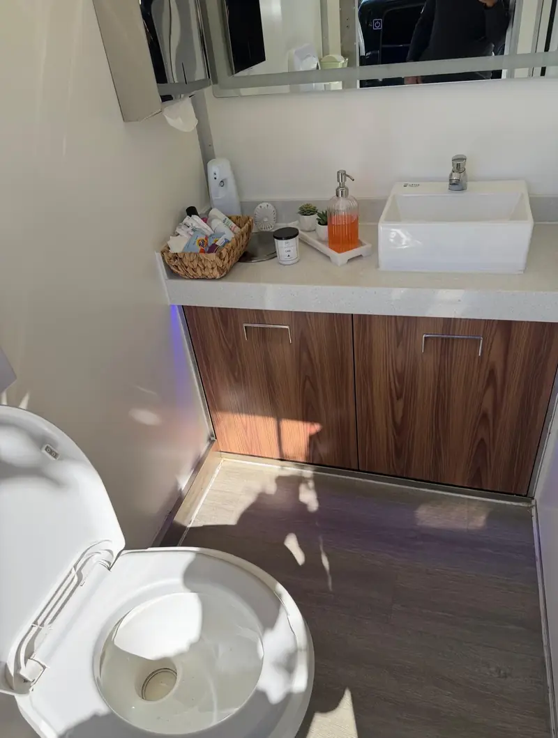 Restroom trailer wood vanity with vessel sink and flushing toilet